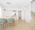 Dining area with wooden table, dining chairs, stairs, open kitchen, white walls, modern ceiling lights