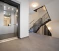 elevator, stairs, tiled floor, white walls, ceiling lights