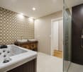 bathroom with walk-in shower, jacuzzi tub, 2 sinks, glass wall