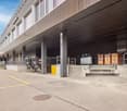 Large industrial building with loading docks, storage containers, and a parking area in the foreground.