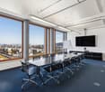 Conference room with large windows, long table, black chairs, whiteboard, TV