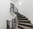 Spiral staircase with granite steps and black metal railing leading to a balcony or upper level
