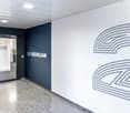 Open entrance hall, large white and blue wall, glass doors, modern design, plant, logo