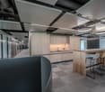 modern office space with wooden desk, chairs, glass walls, and ceiling lights