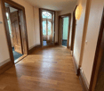 wide hallway, hardwood floors, tall ceilings, light fixtures on the wall