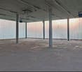 empty room, concrete floor, steel columns, wooden desk, white slat walls, glass windows