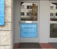 Building entrance, grey door with a sign and glass panel, text in German and English advertising professional and innovative textile cleaning services.