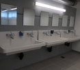3 wash basins, 4 mirrors, grey tiled floor, white tiled walls, lighting and dispensers