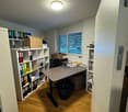 an office room with desk, chair, cabinet, shelves, and a window