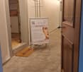 Tiled floor, white walls, open door, welcome mat, information board, corridor