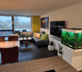modern open space, large glass windows, terrace, dining area, living area, aquarium, fireplace