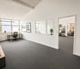 Empty office with desks, chairs, plants, and a motivational sign on the wall.