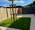 a brick paved garden with a grassy area and wooden fences