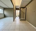 Corridor with tiled floor, glass entrance, and shower area.