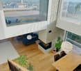 Open floor plan, living room with fireplace, dining area, balcony, hardwood floors, large windows, modern decor