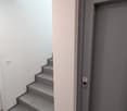 A corridor with tiled flooring, a staircase, and an elevator door with a button.
