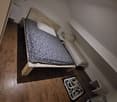 two beds, wooden bedframes, white pillows, dark hardwood floors, light fixtures