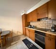 Modern kitchen with wooden cabinets, tiled backsplash, gas stove, built-in oven, kitchen table with chairs