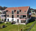 2 story house, brown roof, white walls, balcony, garden, fenced yard