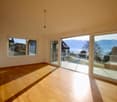 Empty room with large sliding glass doors leading to a balcony and a lake view