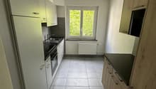 modern kitchen with white cabinets, black countertops, tiled floor, window with view
