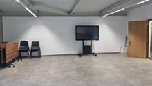room with tiled floor, two chairs, mounted monitor, wooden door