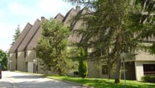 Row of houses with brown roofs, stone walls, windows, and garages