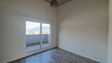 Spacious bedroom with large windows, hardwood-style flooring, and a balcony or terrace overlooking the surrounding area.