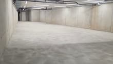 Empty concrete floor, metal beams, pipes, lights, door