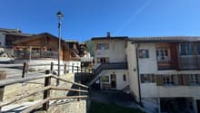 Swiss chalet style house, large wooden balcony, raised ground floor, wooden fencing, garden