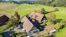 Traditional rural house, nestled in green countryside, multiple outbuildings, car parked in driveway