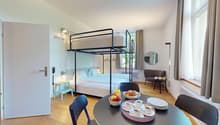 Bunk bed, dining table, armchair, radiator, ceiling lamp, round mirror, window, hardwood floor