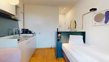 Compact kitchen with sink, faucet, coffee machine, and toaster. Bedroom with a bed, bedside table with lamp, and wardrobe. Modern bathroom with white tiles and wooden floor.