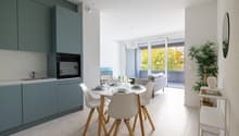modern kitchen with dining area, white cabinets, white countertops, modern appliances, dining table, chairs, balcony with couch, potted plant