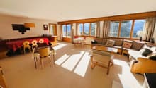 large living room with dining area, wooden furniture, large windows, carpets, picture frame on the wall
