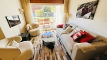 large sofa, coffee table, armchairs, TV, rug, glass door to terrace