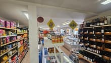 A grocery store with various products on shelves, including snacks, beverages, and condiments. There are also bottles of wine on the shelves.