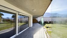 Modern building with glass walls, tiled floor, outdoor terrace, and view of mountains