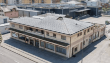 2 story building, gray roof, multiple windows, located in a city