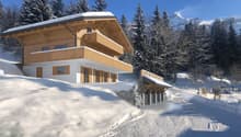 Detached house, wooden and white structure, with wooden balcony on upper floor, in snowy landscape