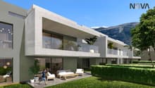 Modern 2 story house, gray concrete, glass windows, several balconies, terrace, yard, mountains in the background