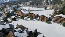 large chalet building, modern architecture, wooden balconies, snow-covered surroundings, surrounded by trees, playground