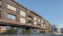 Modern design building with wood panels, balconies, and multiple windows.