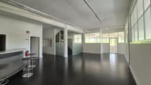 empty room with black floor, three stools, fire extinguisher, large windows, white walls