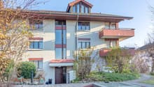 2 story house, white walls, red trim, multiple balconies, garden, entrance with awning