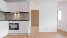 modern kitchen with white cabinets, wooden floor, built-in oven, extractor hood, power outlets, and a window