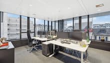 modern office setup with desks, chairs, monitors, office equipment, large windows with city view