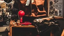 Cluttered room with various items such as a red lamp, toy cars, and framed posters on the walls.
