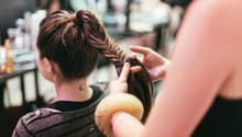 Woman with brown hair getting her hair braided by another woman