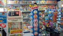 Candy store with magazines, shelves with candy and toys, candy dispenser, counter with candies, magazines rack